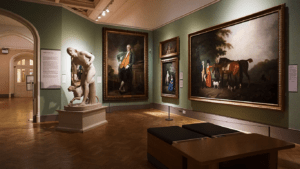 an art gallery with paintings on the walls and statues on the floor