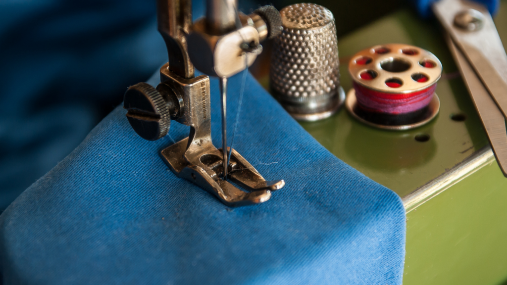 a close up of a sewing machine with blue fabric