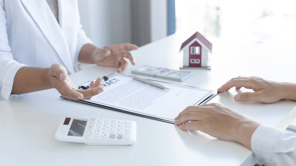 a person holding a contract with a house model on top of it