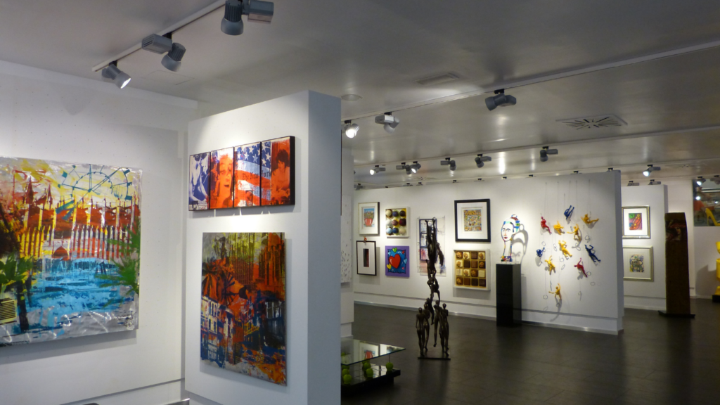 an art gallery with paintings on the walls and statues on the floor