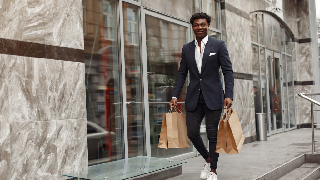 Two people walking down the street holding shopping bags.