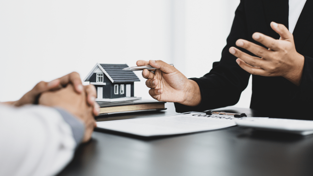 two people sitting at a table with a house model in front of them